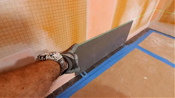 Tile installer working on shower wall with laser level – Beaumont home